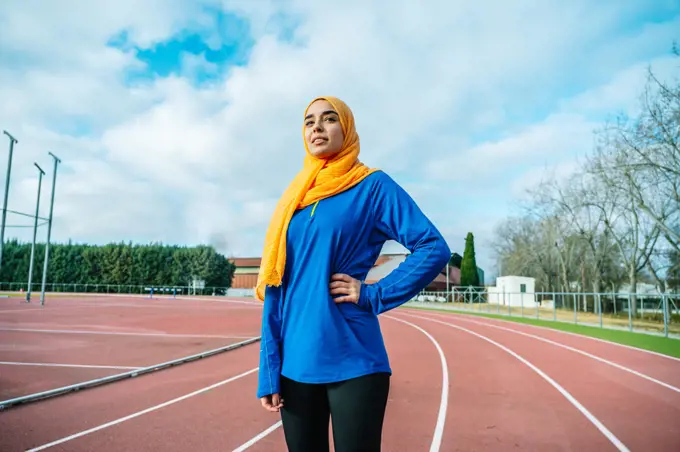 Smiling Arab woman standing on track field during training
