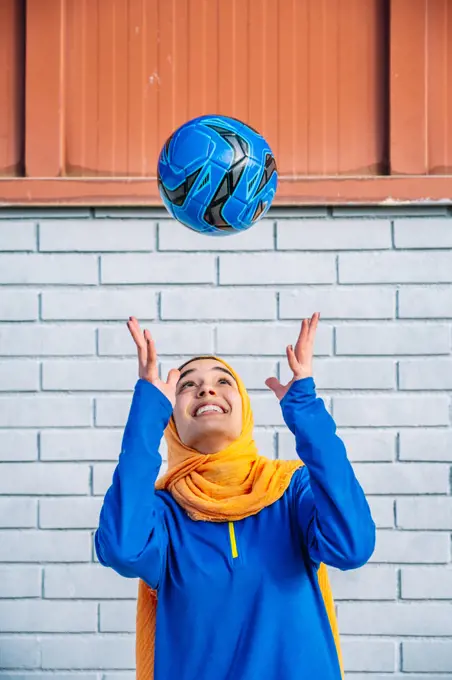 Smiling ethnic woman throwing football ball
