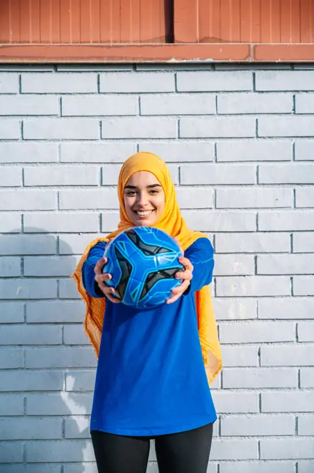 Smiling Arab female outstretching hands with ball