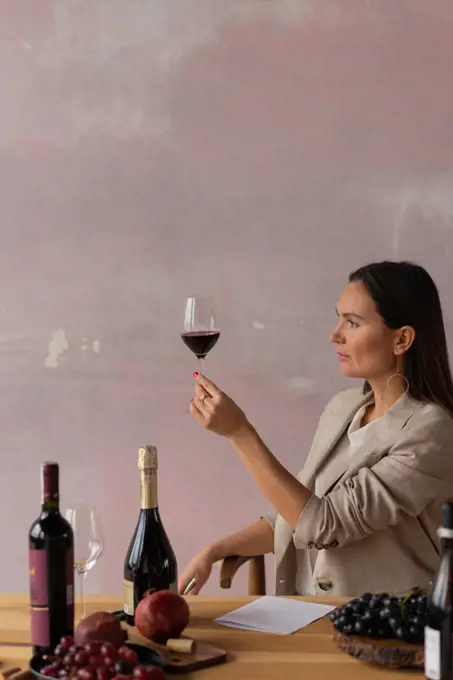 Female sommelier looking at color of wine in glass, making degustation