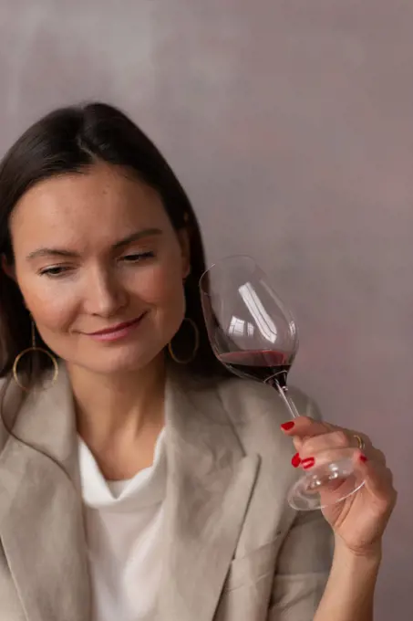 Smiling woman with glass of wine on pink studio background