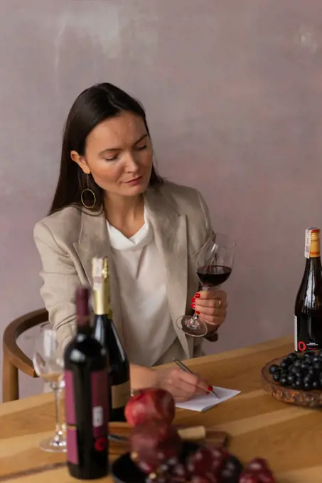 Beautiful woman sommelier writing notes testing wine drink