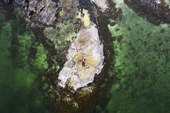 Aerial view of family lying on rock surrounded by clear green water