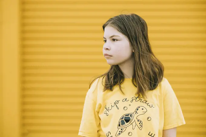 Young girl standing against a yellow wall