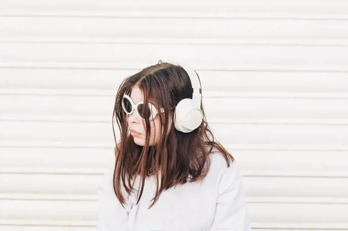 Girl standing outside wearing sunglasses and headphones