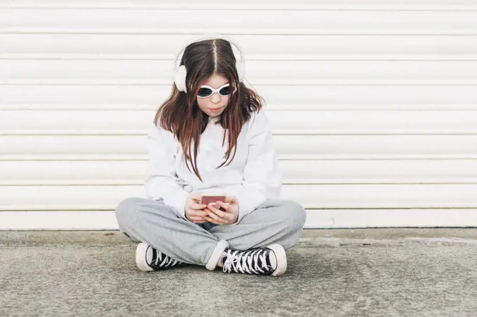 Girl sitting wearing sunglasses and listening to music