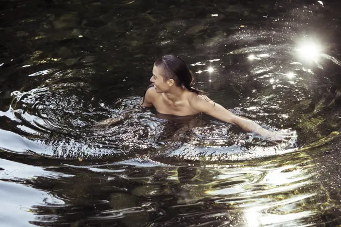 Androgynous young person wading in luscious water