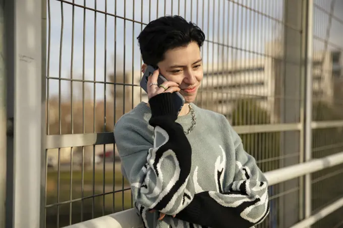 Lesbian girl talking on her smartphone while smiling outdoors