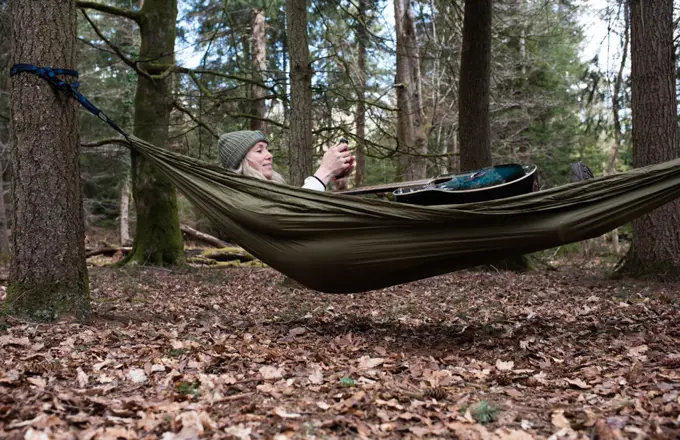 woman sat in a hammock with guitar looking at her mobile phone