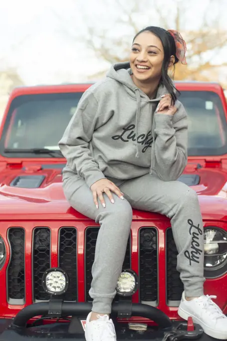 Indian girl in sweatpants and hoody on Jeep hood