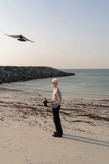 Albino man standing at the beach holding a hat