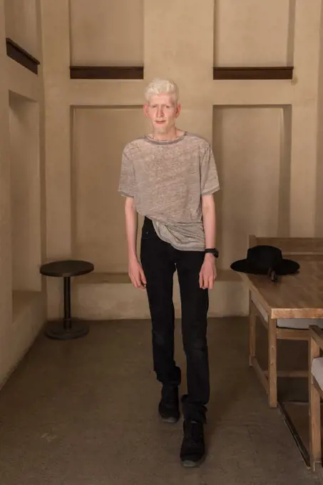 Albino man standing by the wall full length  portrait