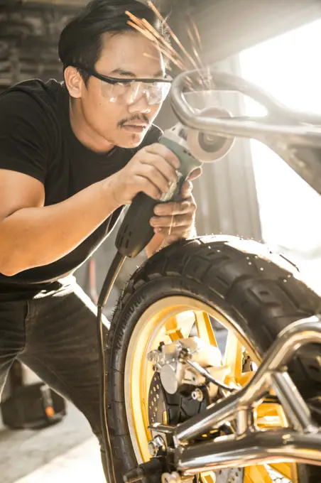 mechanic working on motorcycle at custom bike shop in Bangkok