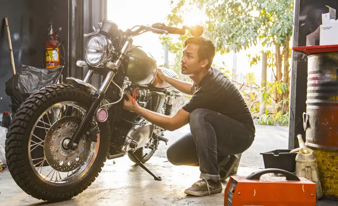 mechanic working on motorcycle at custom bike shop in Bangkok