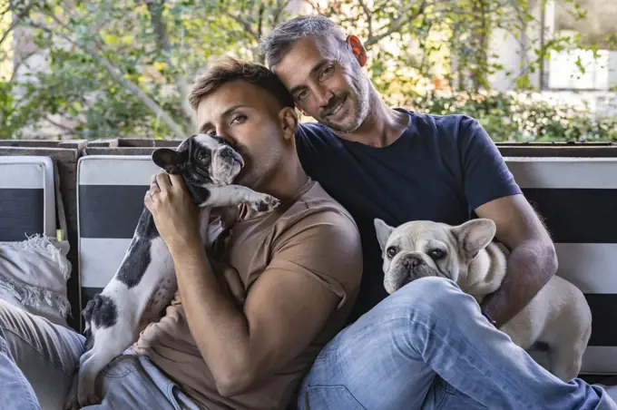 Portrait of a gay male couple and their french bulldogs.