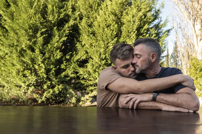 A young man hugging his husband. Both with eyes closed. copyspace