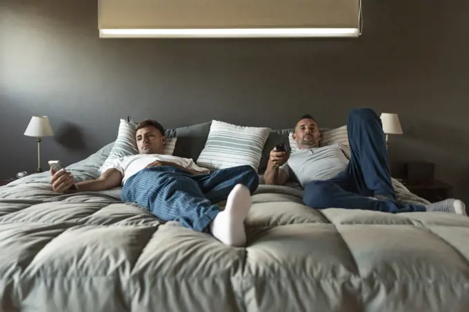 Gay male couple relaxing in bed.