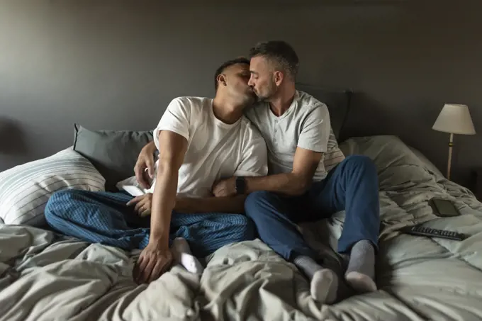 Gay male couple kissing in bed