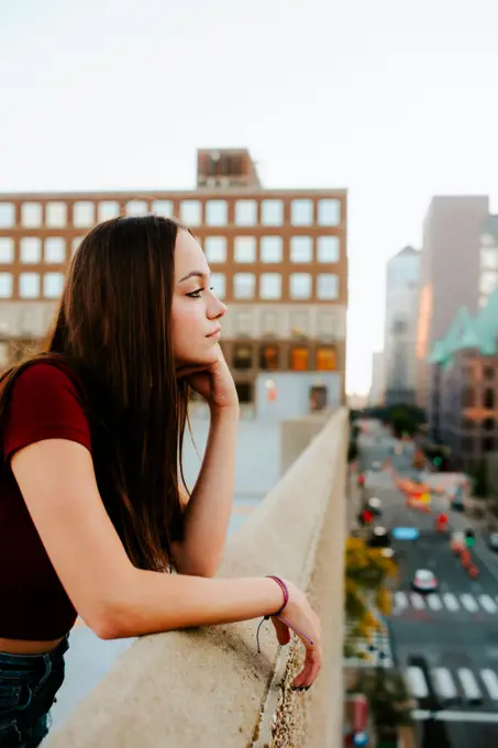 teenage girl gazing over the edge of a garage rooftop