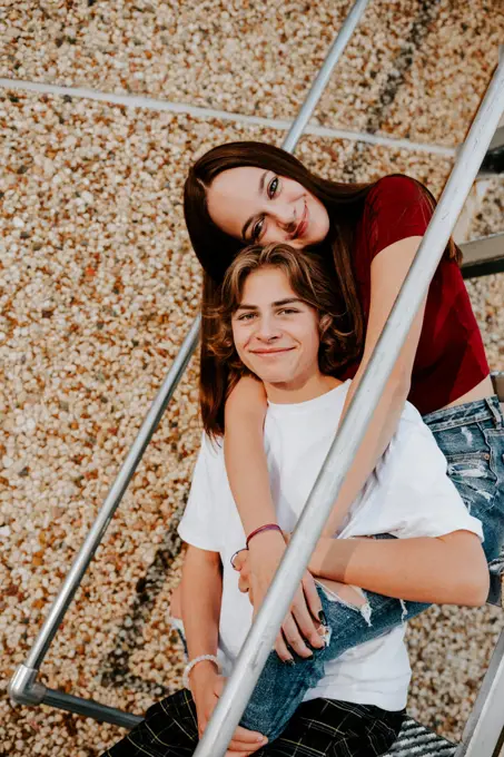 happy smiling teen boy and teen girl sitting on stairs