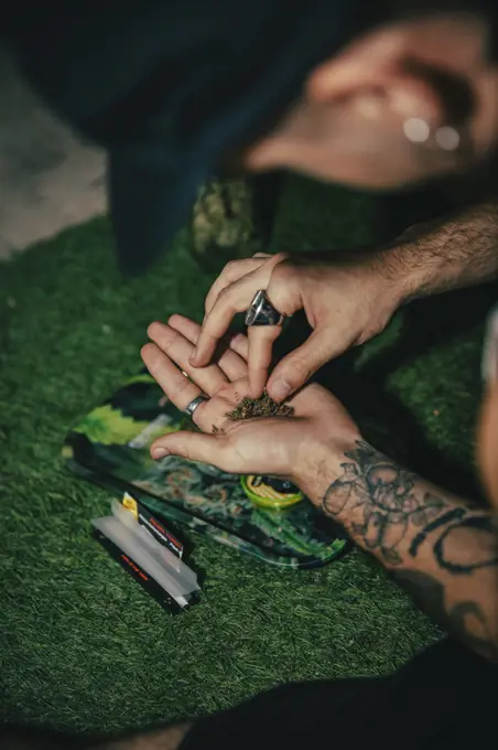 Tattooed guy rolling a marijuana joint