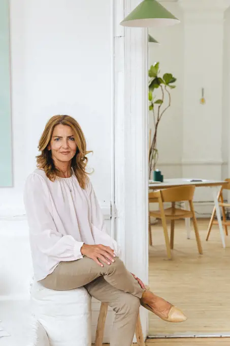 Smiling mature businesswoman sitting on sofa in creative office