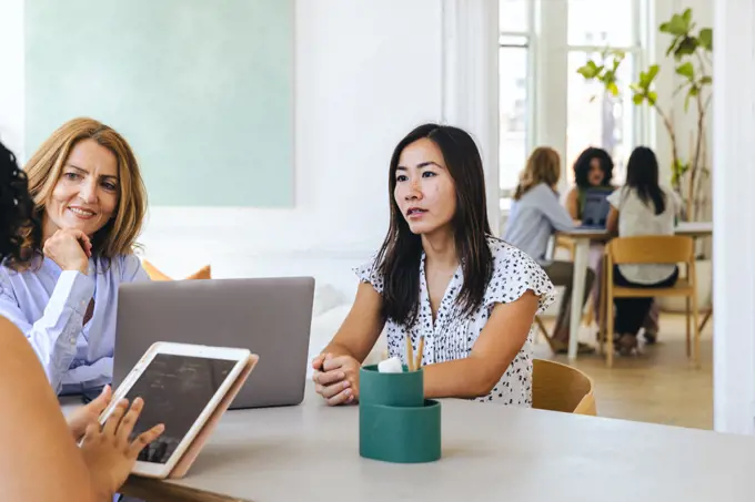 Businesswoman holding ipad discussing strategy with female colleagues