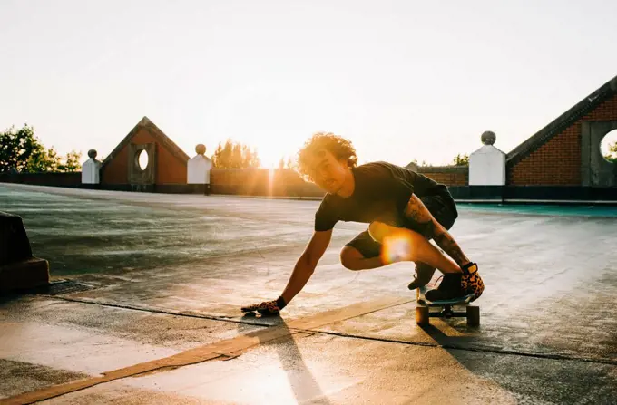 portrait of a man skateboarding in a car park at sunset