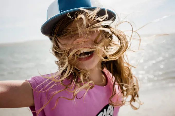 candid portrait of girl at the beach with her hair blowing in the wind