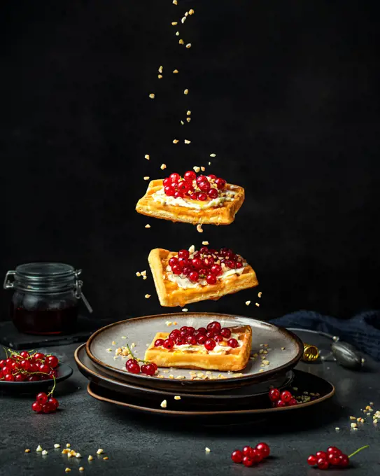 Belgian waffles levitation with berries and honey on black .