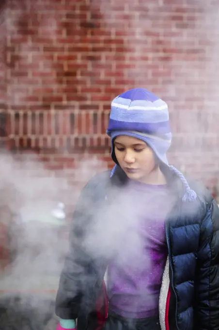 A beautiful serious child standing in smoke gazes down