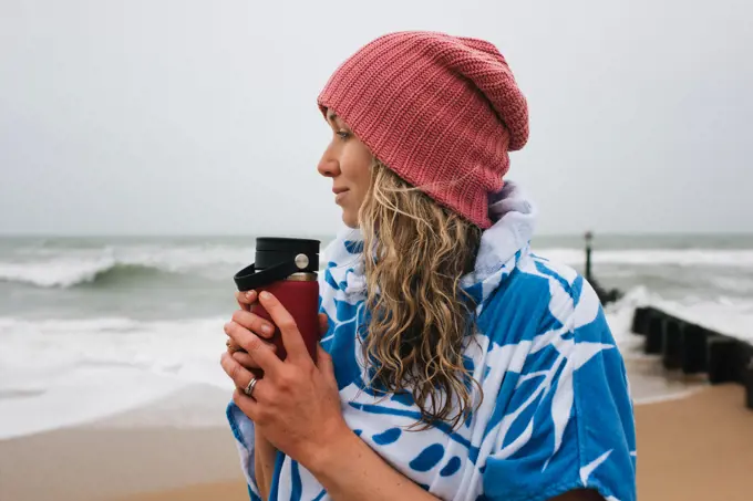 Woman holding a warm drink after cold water swimming in the sea
