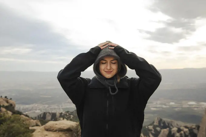 Portrait of a girl in a jacket and balaclava on top of a mountain