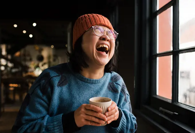 Asian woman laughing having coffee in a cafe