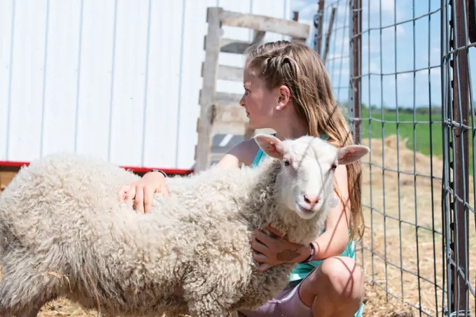 Blond tween girl with a white lamb.