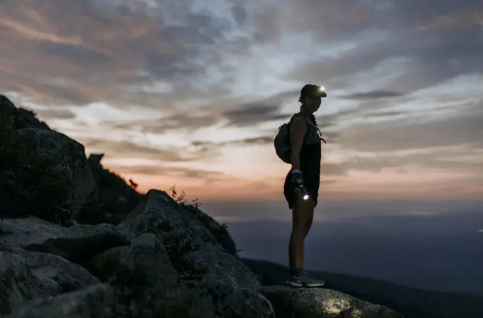 female hiker with headlamp hikes Katahdin at sunrise