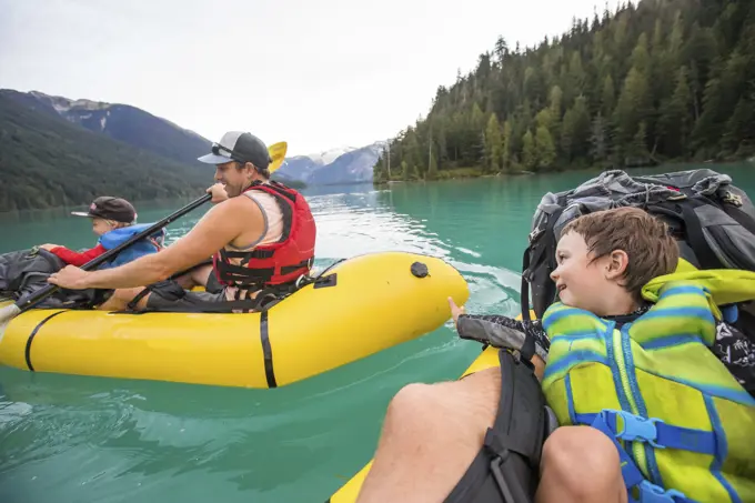 Young boy reaches out to touch his friends inflatable boat.