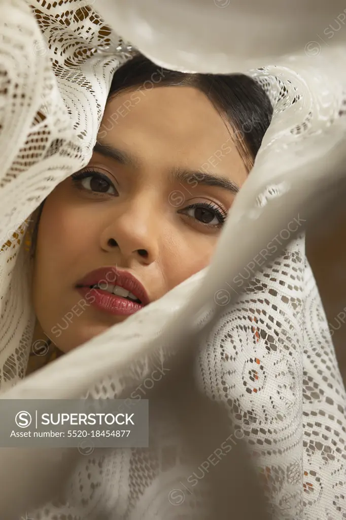 PORTRAIT OF A YOUNG WOMAN LOOKING AT CAMERA WRAPPED IN WHITE CLOTH