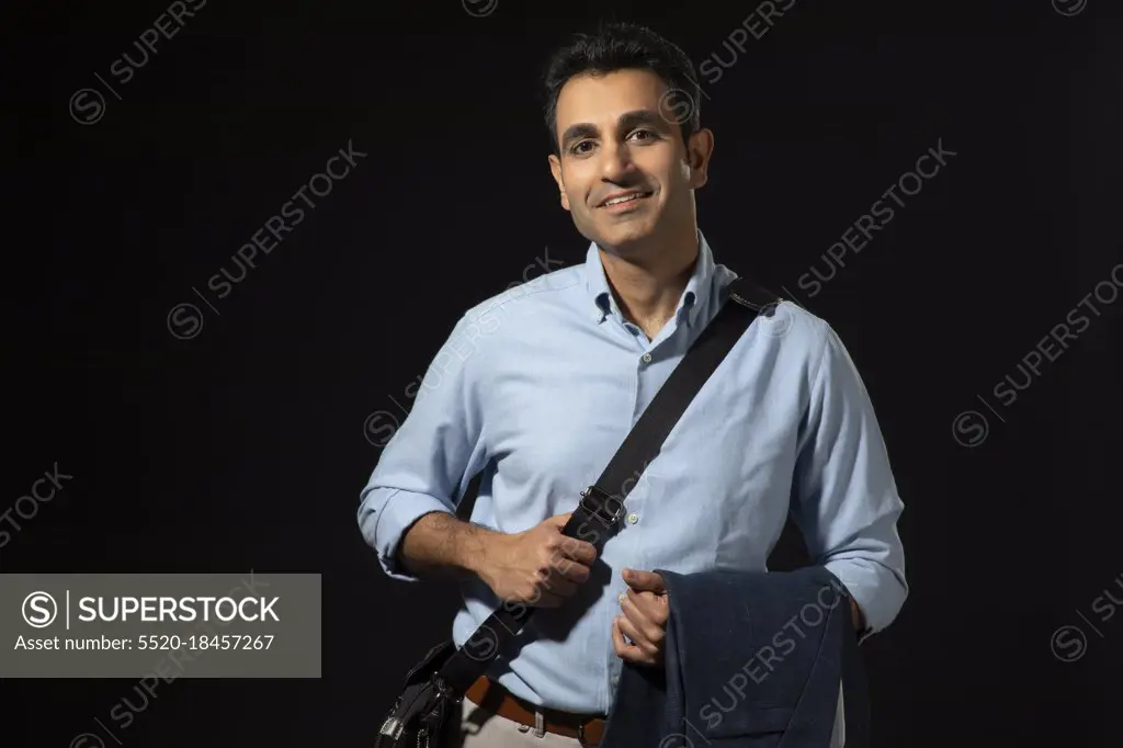 A CORPORATE EMPLOYEE STANDING WITH BAG AND BLAZER READY TO GO