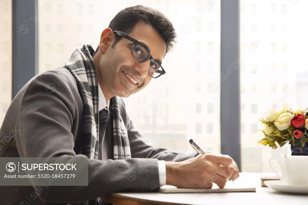 A HAPPY CORPORATE PROFESSIONAL SITTING AND LOOKING AWAY WHILE WORKING IN OFFICE