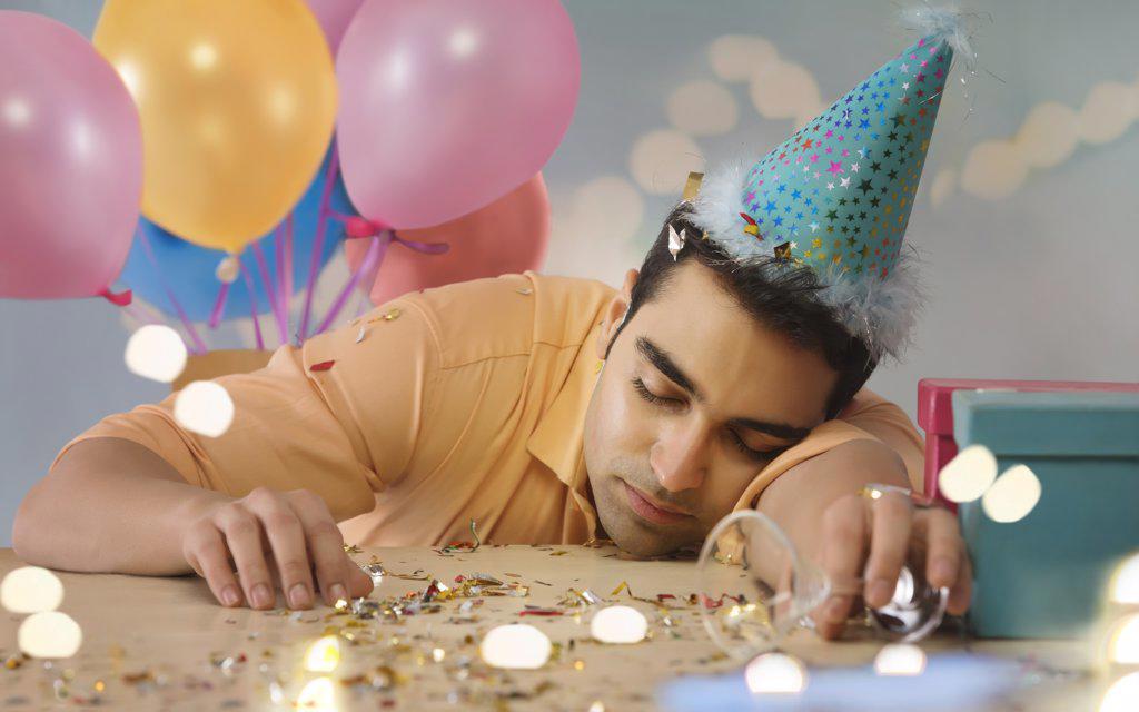 Young man sleeping on the table after being drunk at a party.
