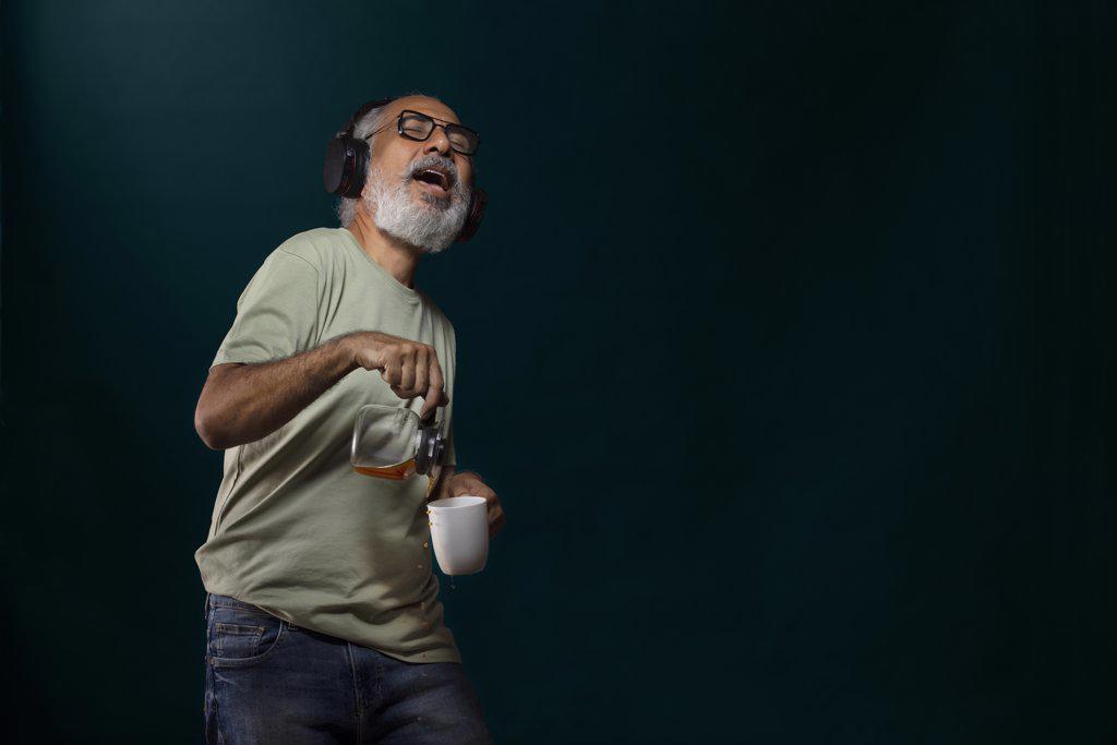 A HAPPY OLD MAN SPILLING COFFEE WHILE DANCING TO MUSIC