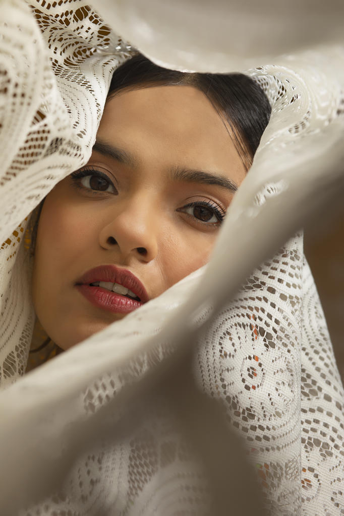 PORTRAIT OF A YOUNG WOMAN LOOKING AT CAMERA WRAPPED IN WHITE CLOTH
