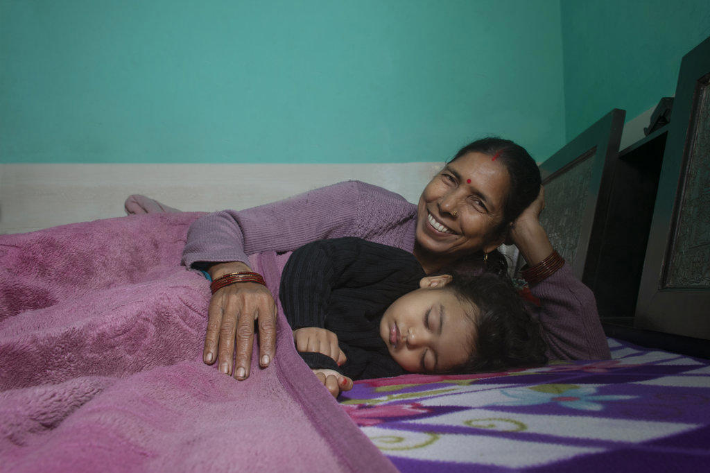 Grandmother and her little granddaughter sleeping together in bed. India