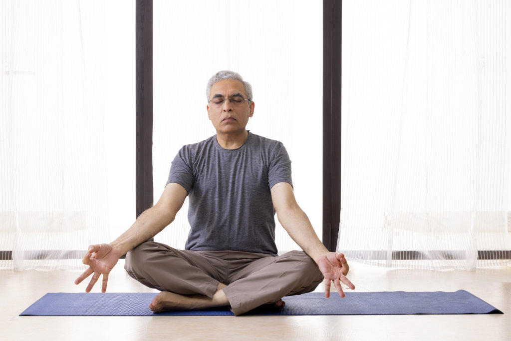 Portrait of an active senior man meditating at home