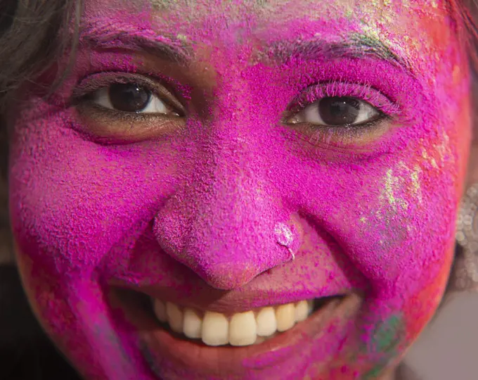 Portrait of a woman smiling with pink gulal on her face on Holi
