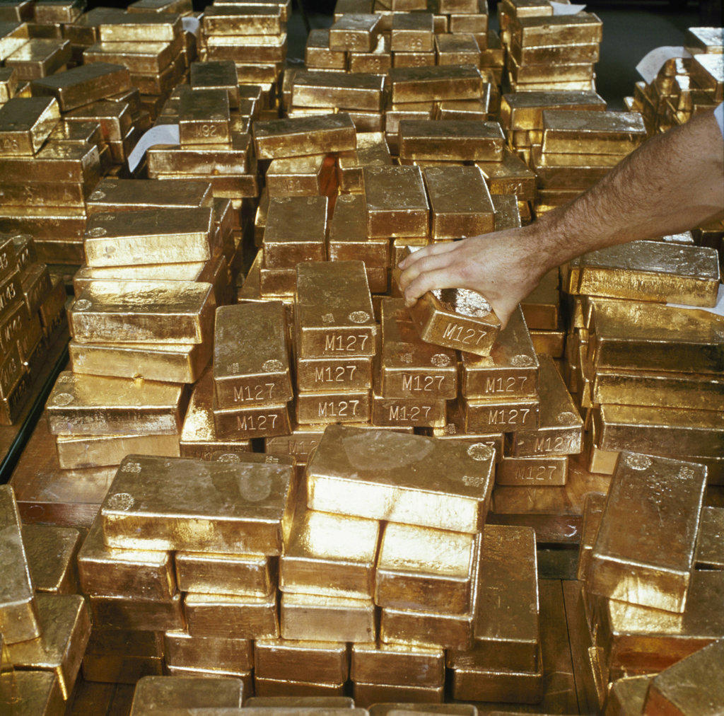 Close-up of a person's hand arranging gold bars, South Africa