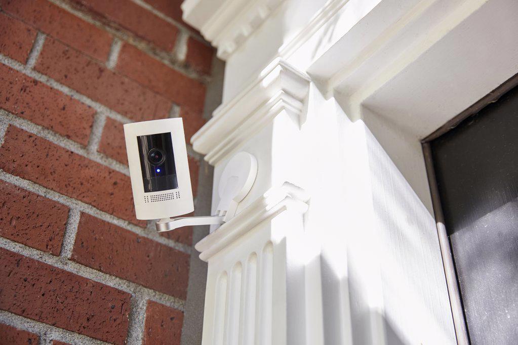 A outdoor home security smart home technology camera looking directly into camera with recording light on.