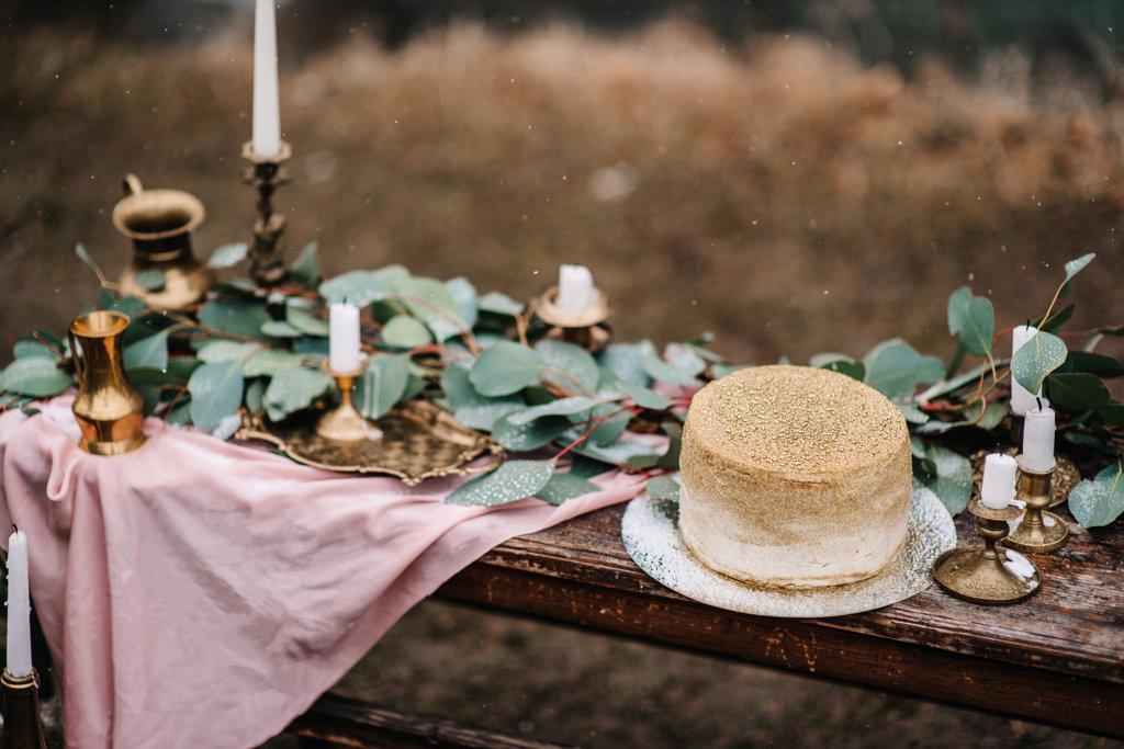 wedding decor with a golden cake on a wooden bench against a waterfall background