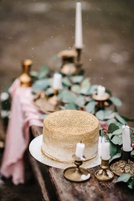 wedding decor with a golden cake on a wooden bench against a waterfall background
